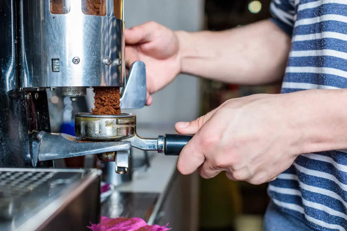 male barista cleaning coffee machine