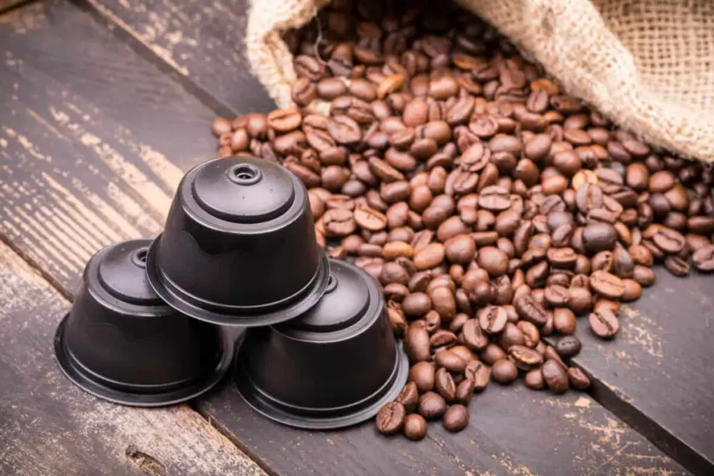 coffee beans in burlap bag beside nespresso capsules