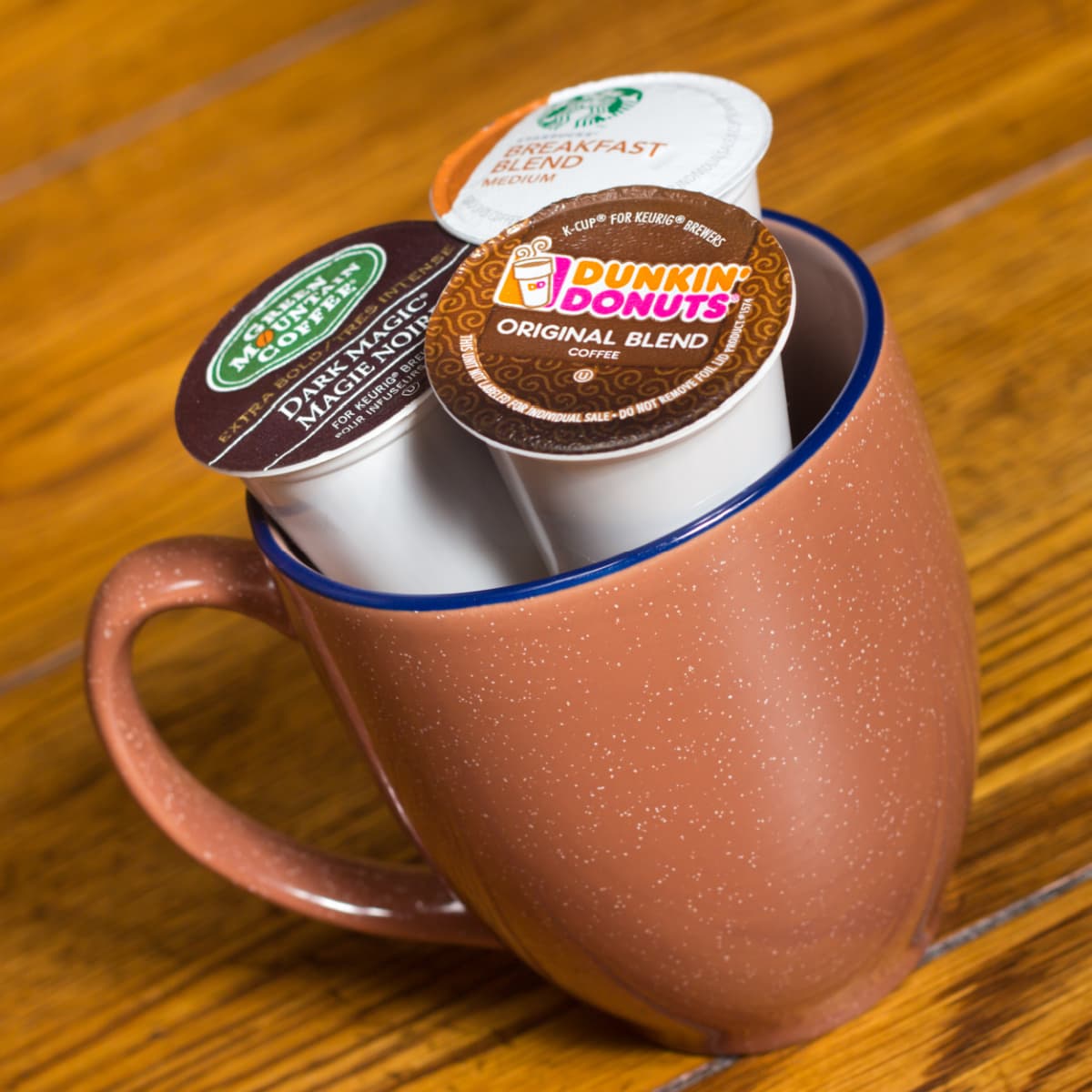 three coffee pods in orange mug with blue rim