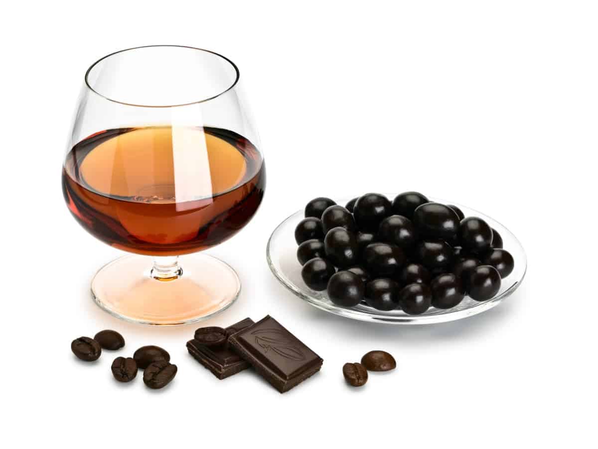 glass of cognac, chocolate pieces, and chocolate covered coffee beans