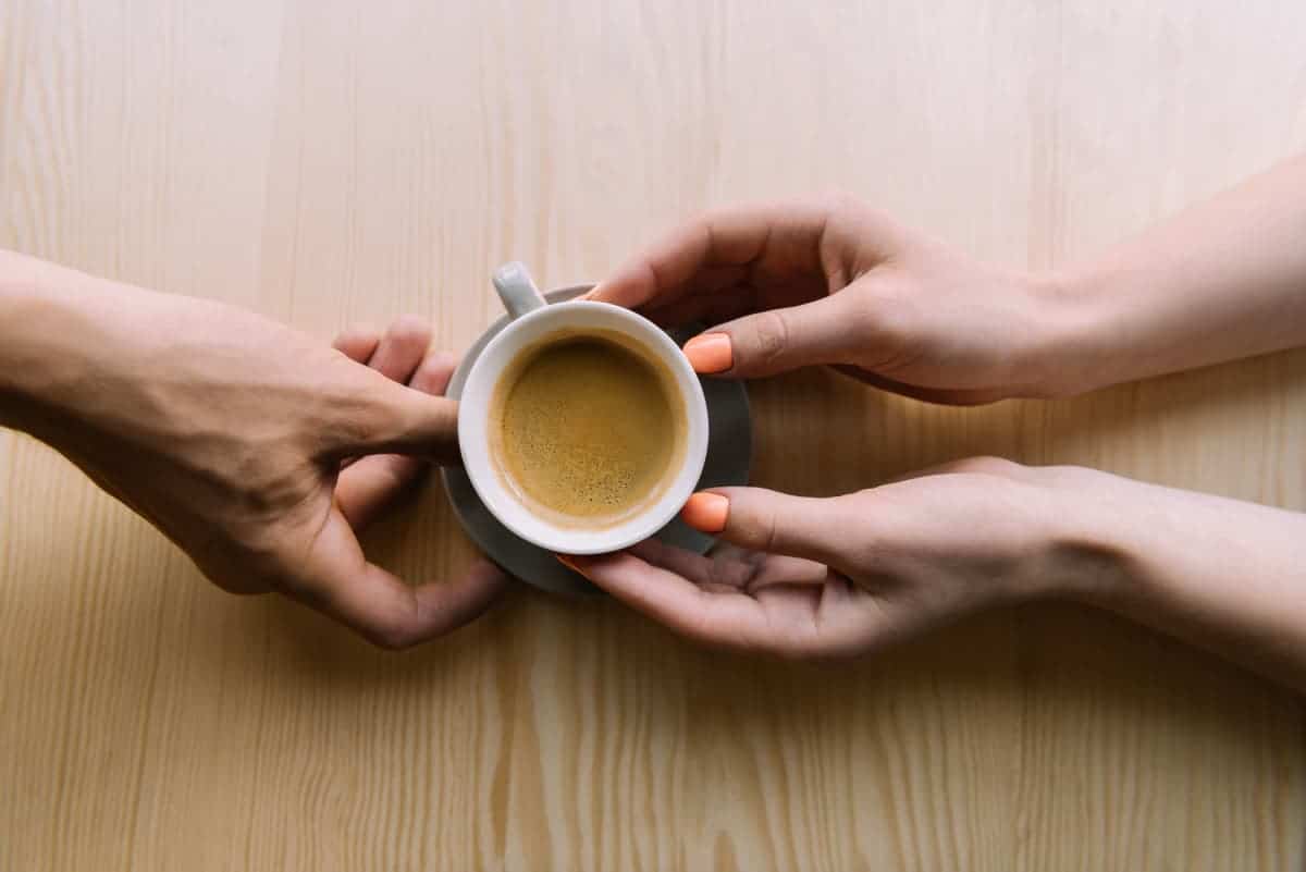 man and woman holding coffee cup together