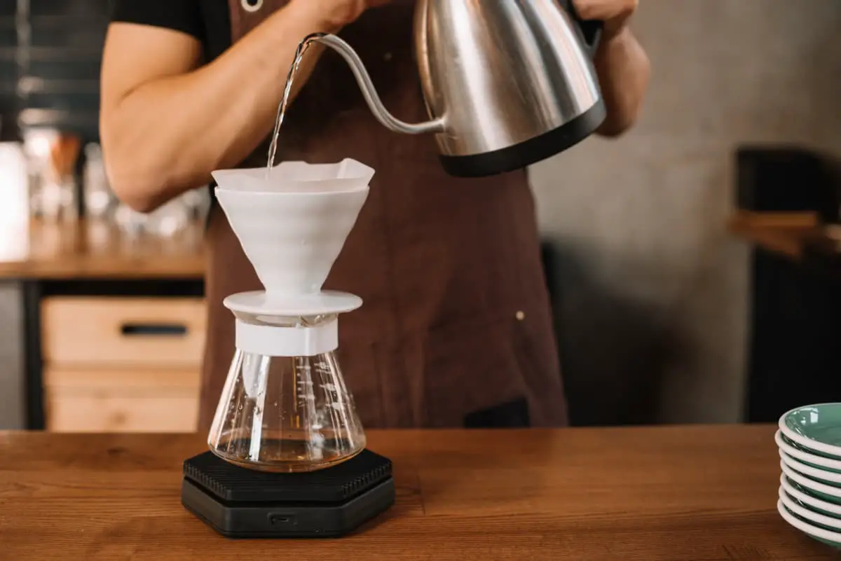 woman in brown apron making pour over coffee