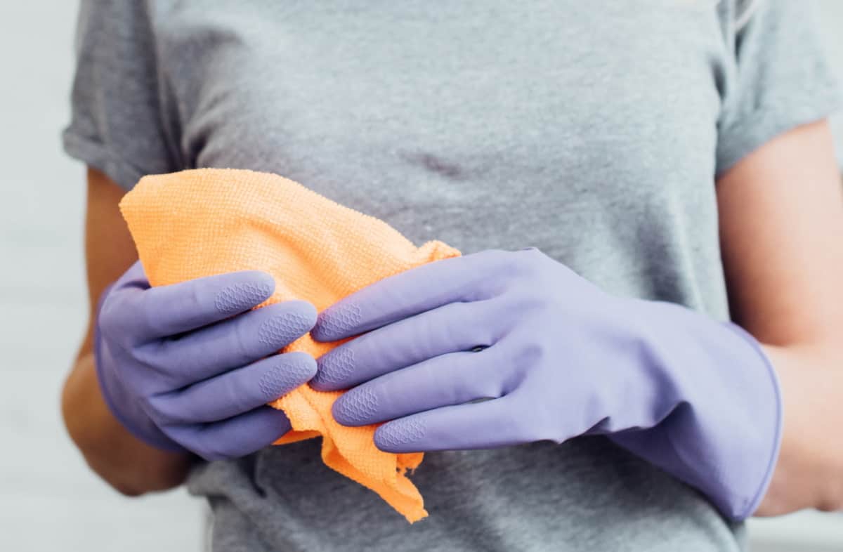 Woman with rubber gloves holding cleaning cloth.