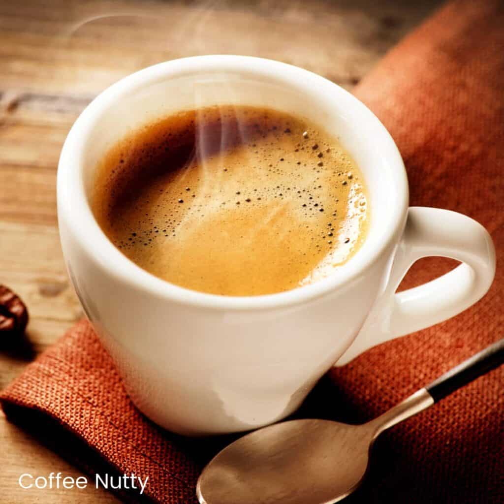 Steaming hot espresso on rust napkin beside spoon.