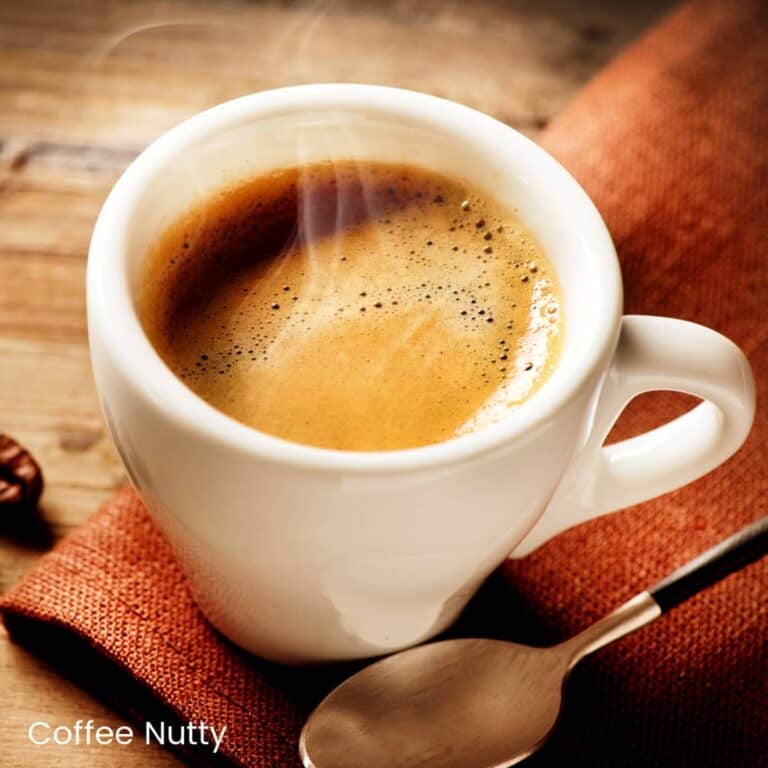 Steaming hot espresso on rust napkin beside spoon.