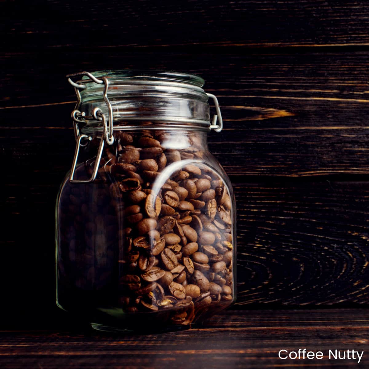 Glass jar of coffee beans with dark background.