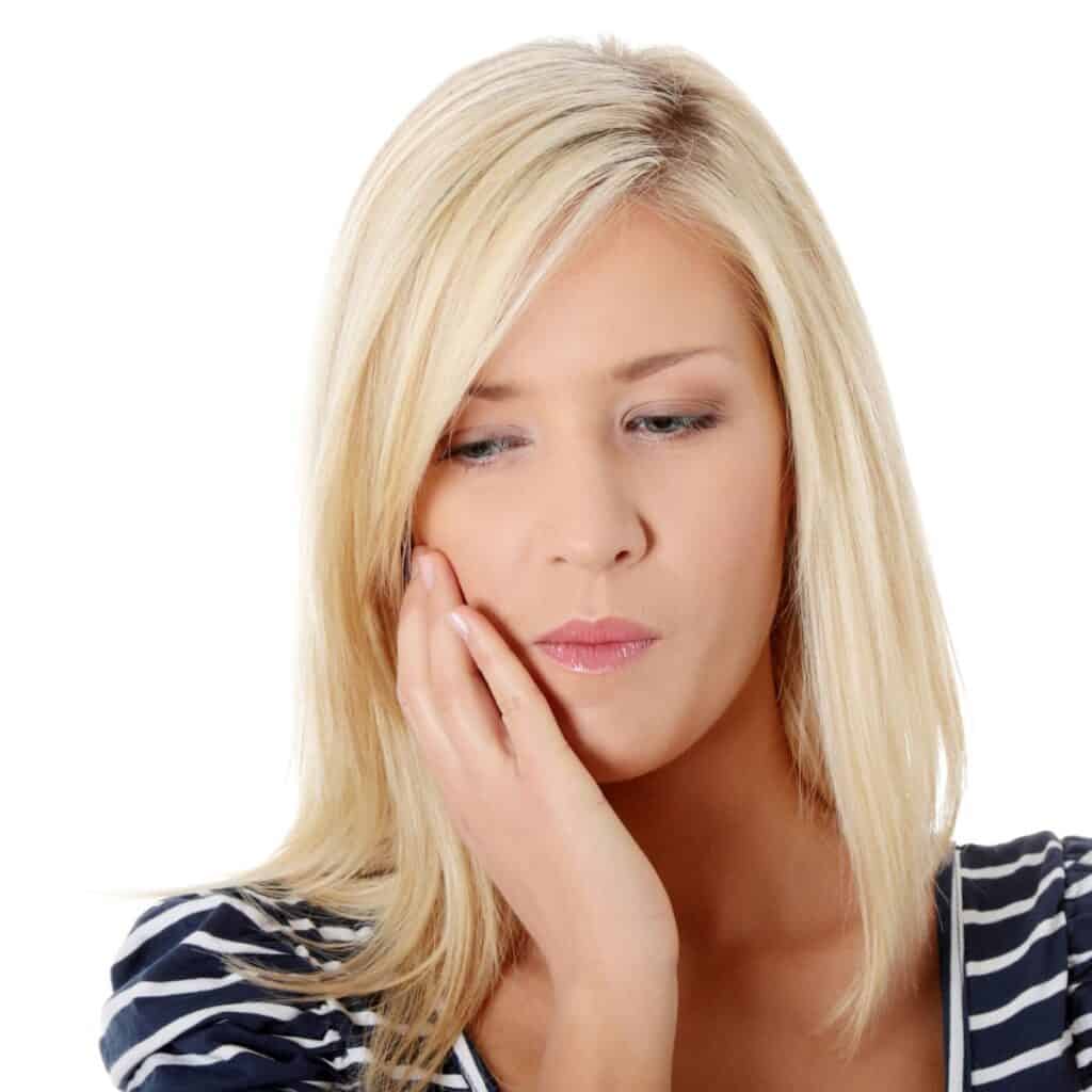 Blonde woman holding her mouth appearing to have sore tooth.