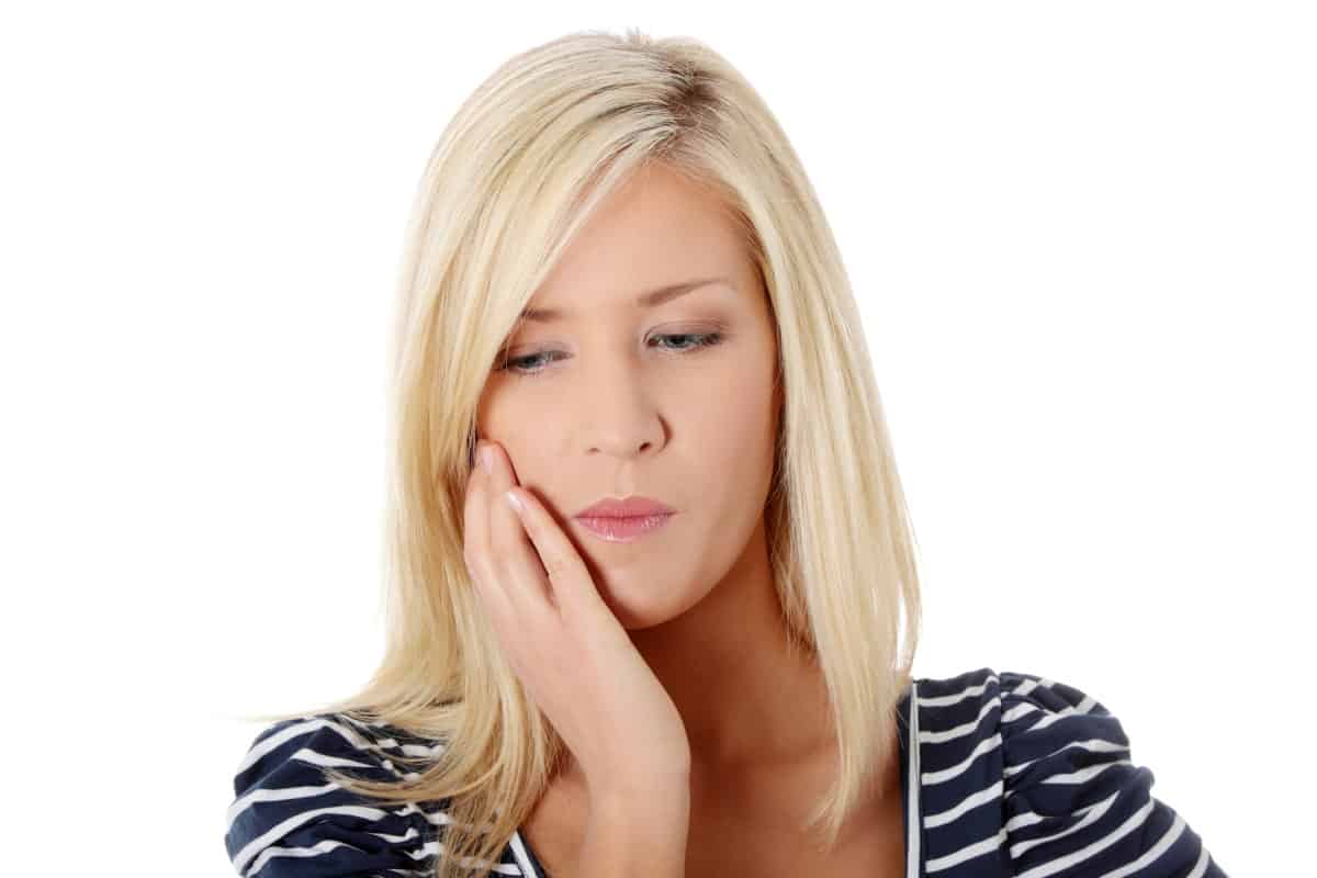 Blonde adult woman holding mouth with sore tooth.