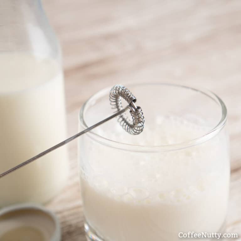 Milk frother in half full glass of milk.
