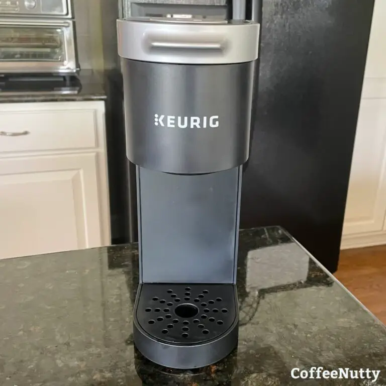 Keurig coffee maker in black sitting on green granite counter.
