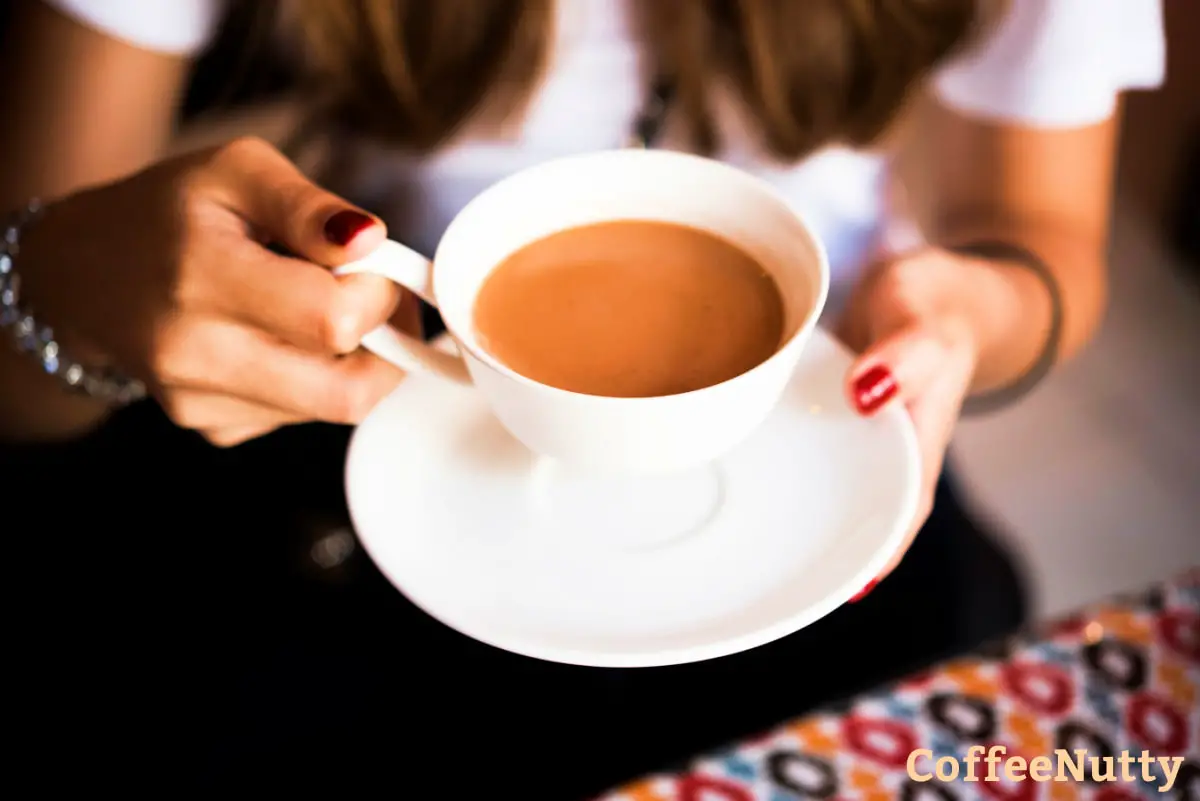 Woman holding cup of masala chai tea latte.