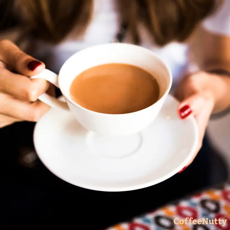 Masala tea in white cup held by woman.