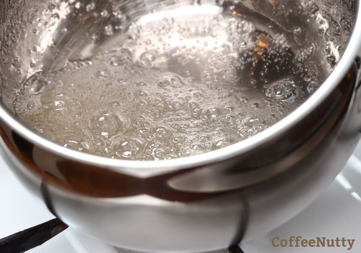 Boiling sugar and water to make a simple syrup.