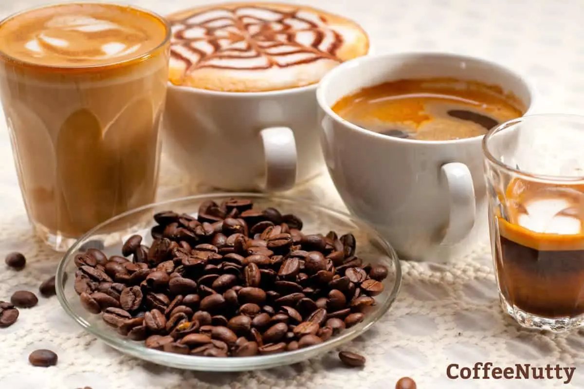 Various types of coffee on a light colored table by coffee beans on a dish.