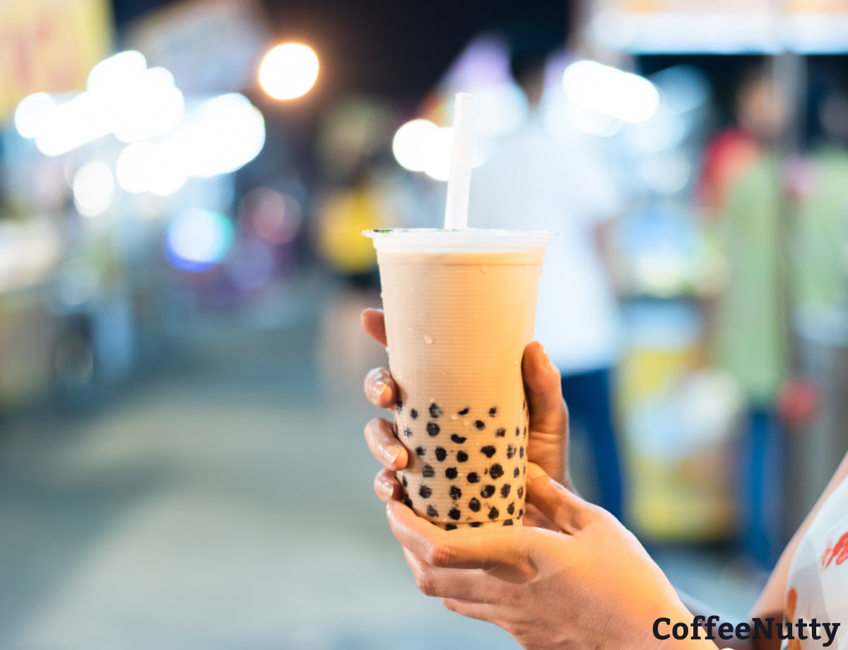 Coffee milk tea in clear cup with tapioca pearls settled in bottom of cup.
