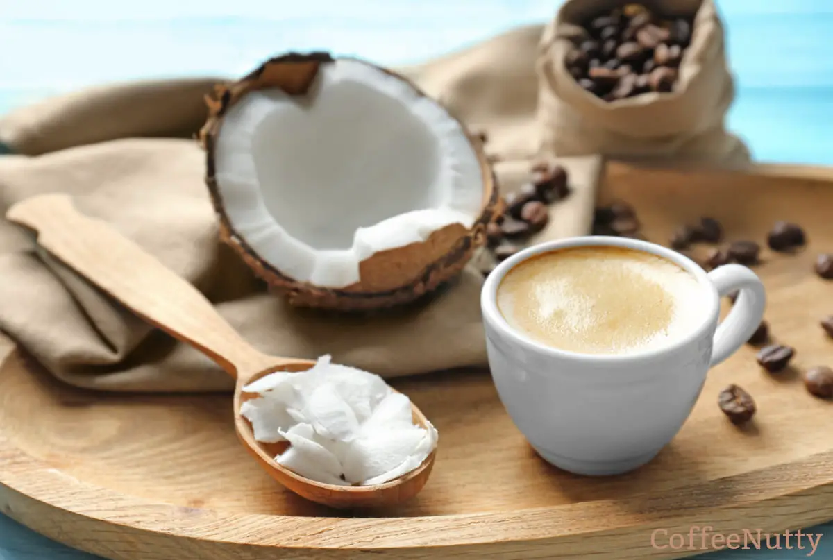Coconut flakes being used to sweeten a cup of coffee sitting on wooden plate.