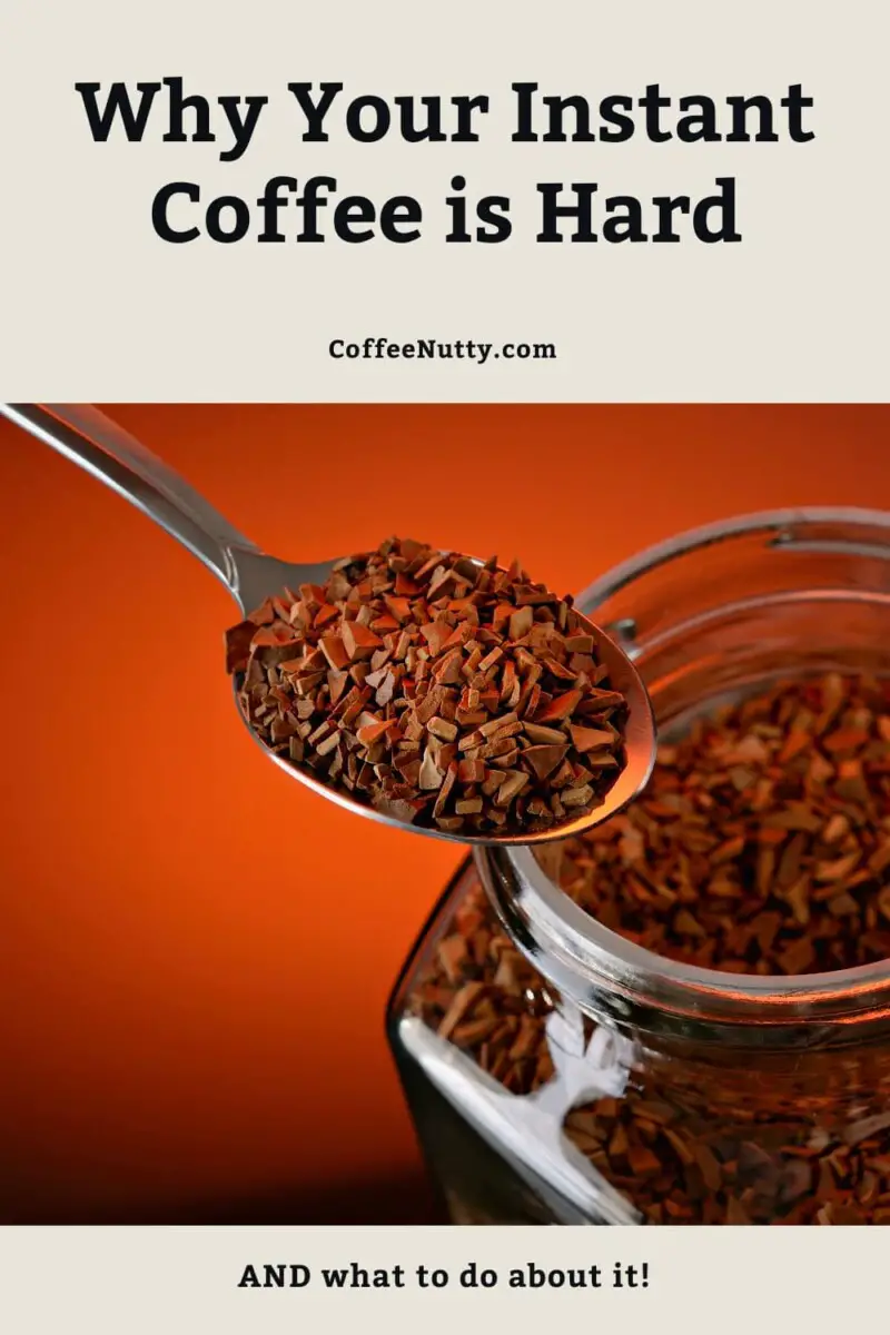 Instant coffee being scooped out of glass jar in spoon.