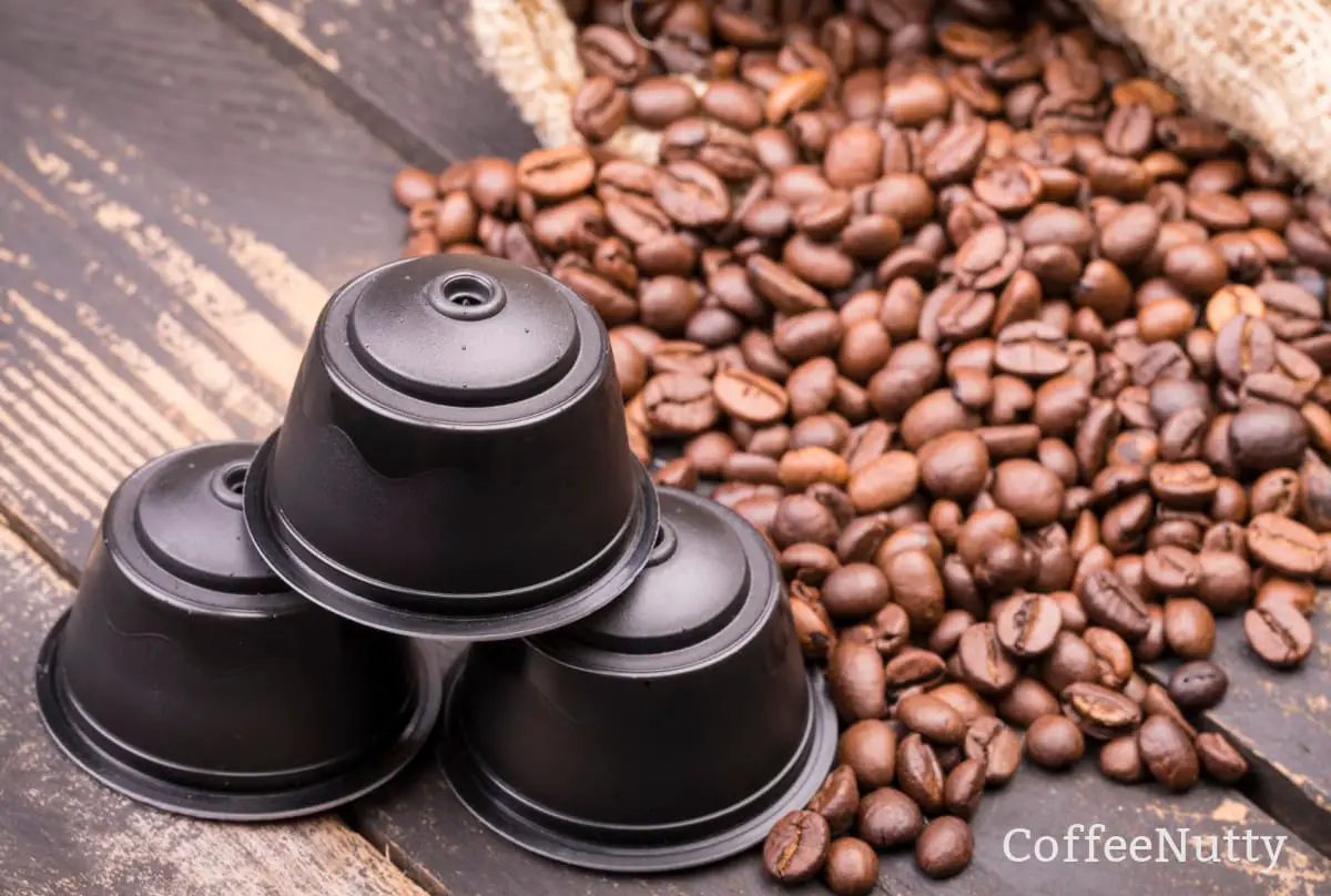 Nespresso capsules sitting on table be coffee beans spilling out of burlap sack.