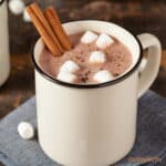 Hot chocolate in white mug with marshmallows and cinnamon sticks-coffeenutty.com.
