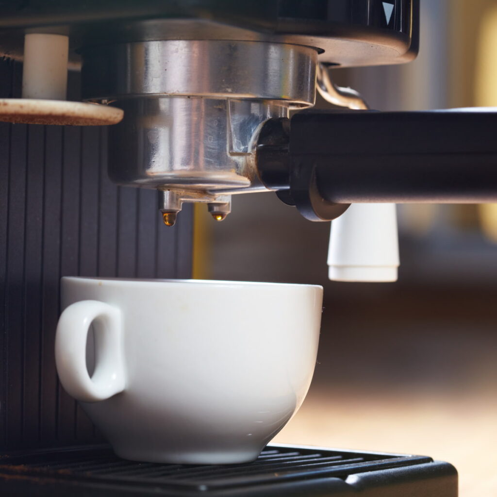 Coffee dripping from machine into white mug.