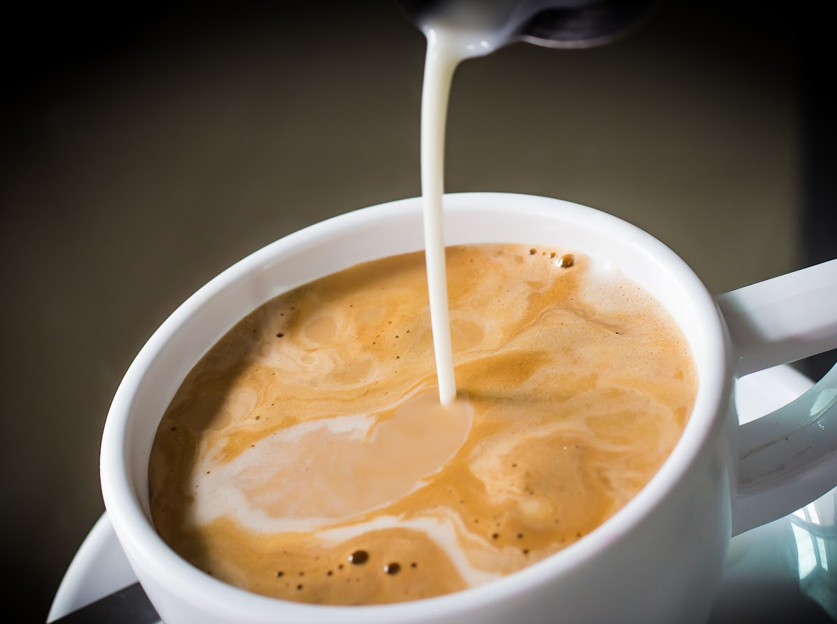 Milk being poured into coffee cup.