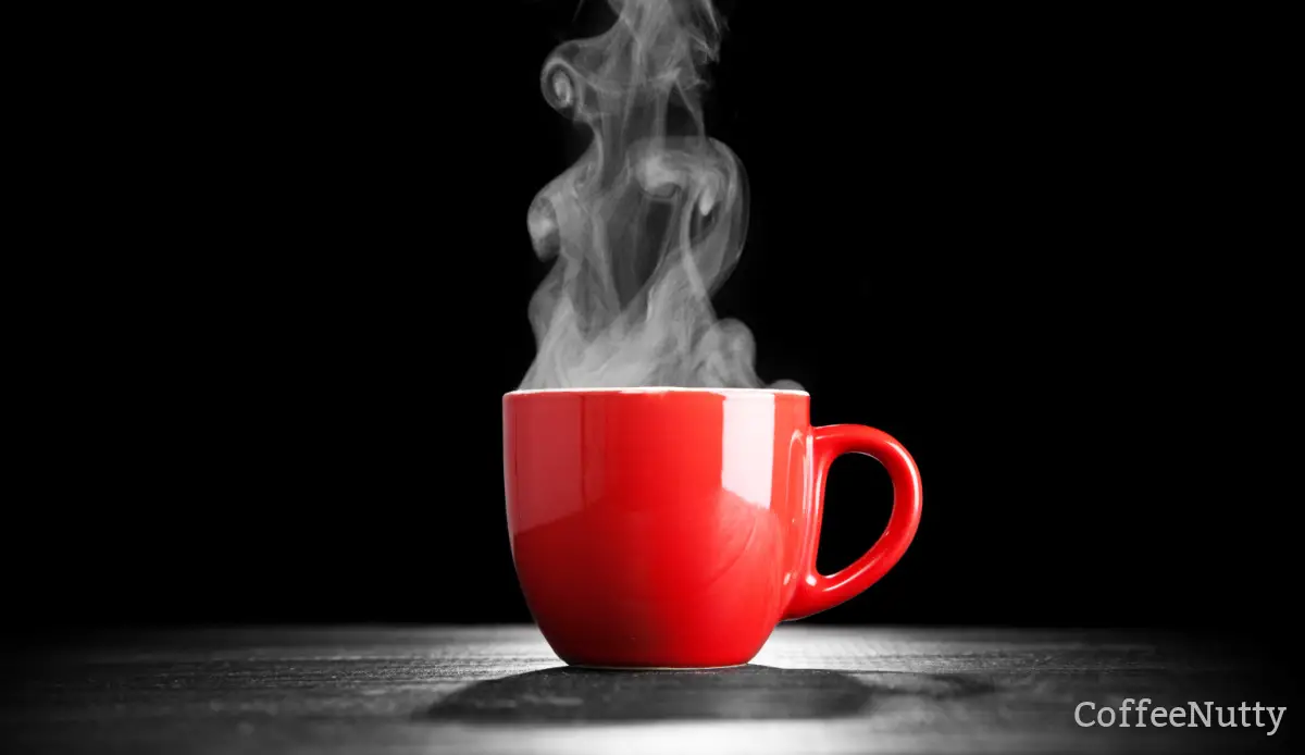 Red coffee mug with steaming hot coffee inside - black background.