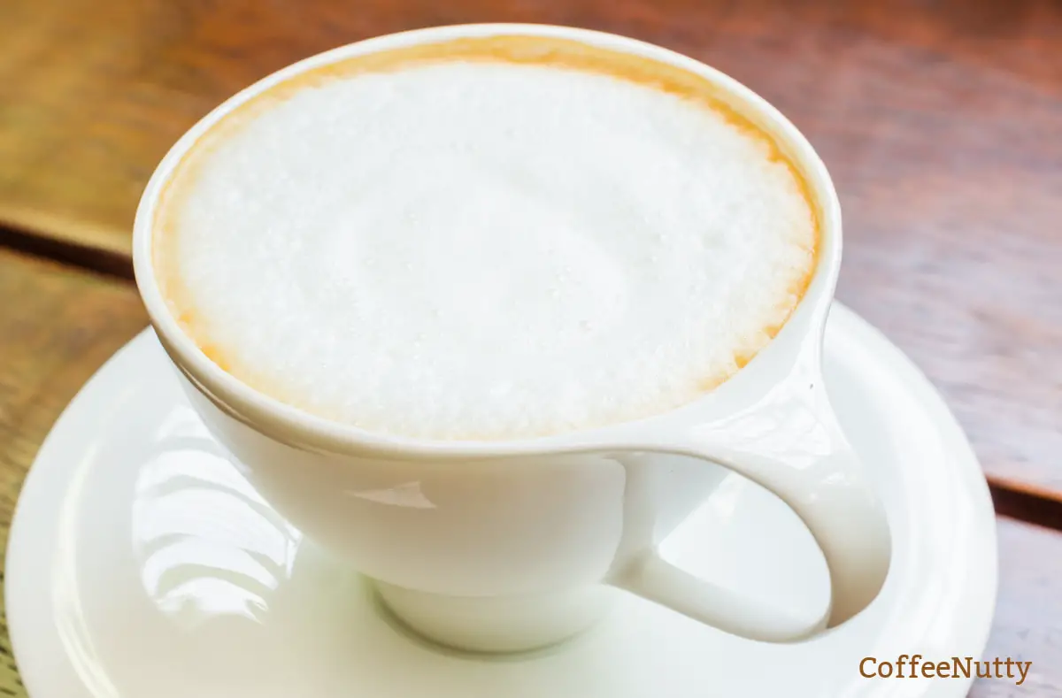 Frothed milk on a coffee beverage within a white mug.