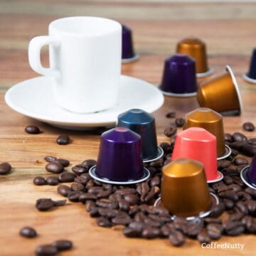 Nespresso capsules beside coffee mug and coffee beans.