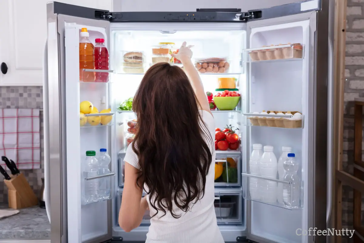 Woman looking at food items in refrigerator.